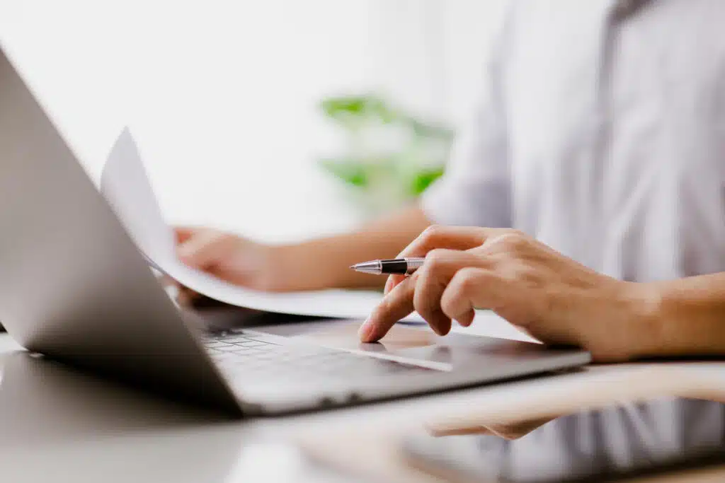 A lawyer takes notes on a notepad while browsing legal documents in his legal document management system